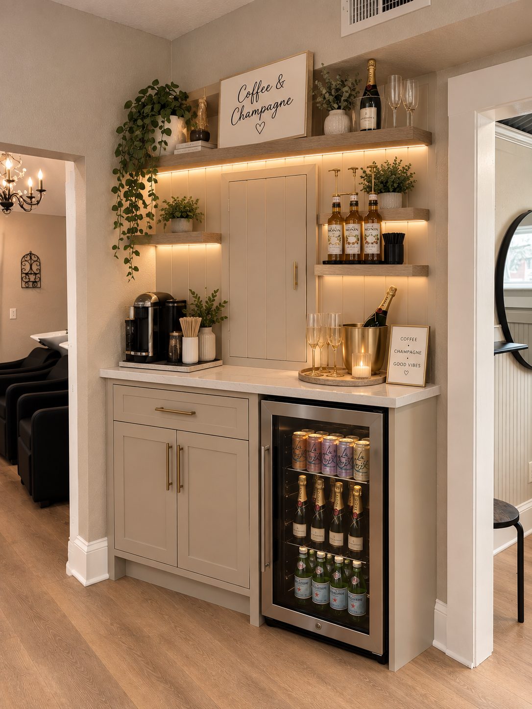The salon's coffee and champagne bar with lit shelves, a beverage fridge and champagne on ice